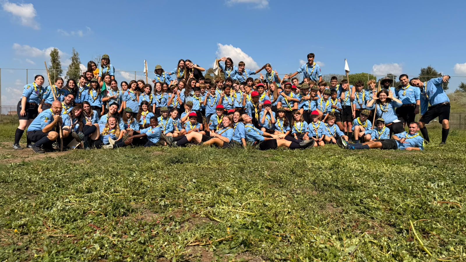 Foto di gruppo di ragazzi, ragazze e capi del Roma 113 in uniforme su un prato